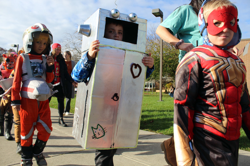 students in halloween costumes parade on sidewalk