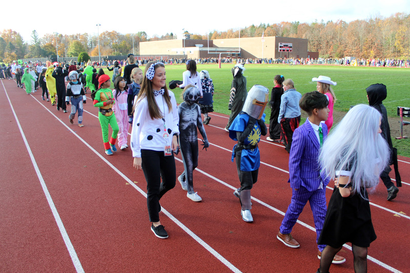 students in halloween costumes parade on track